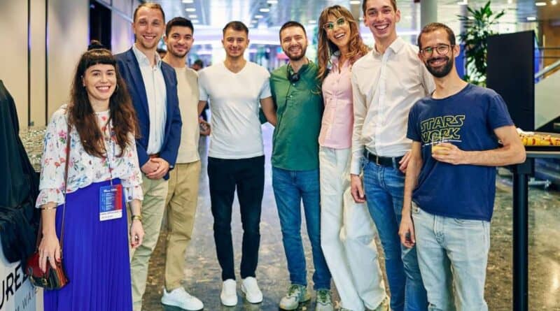 Groupe de 8 jeunes syndicalistes européens en arc de cercle dans le hall lors du congrès 2025 Industriall Europe